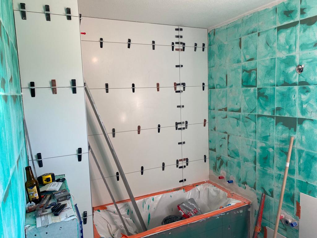 pose de carrelage au mur dans une salle de bains à Douvaine