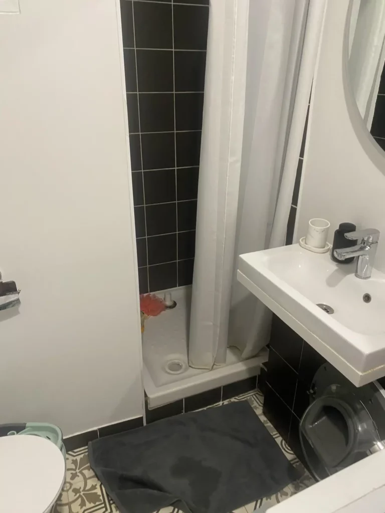Petite salle de bains rénovée à Annemasse avec carrelage noir et blanc.