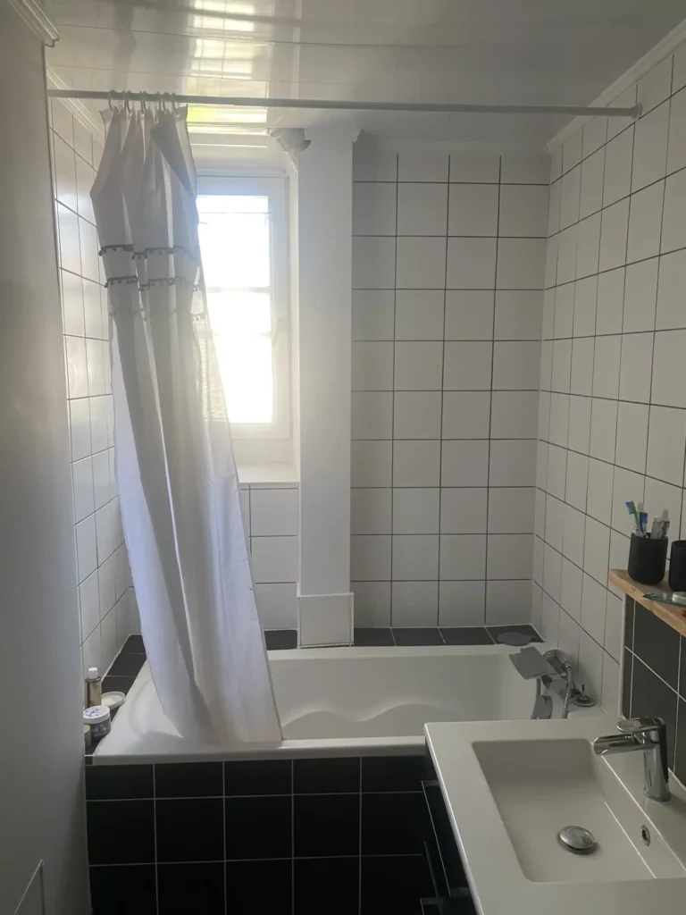 Salle de bains rénovée à Annemasse avec carrelage blanc et baignoire moderne.