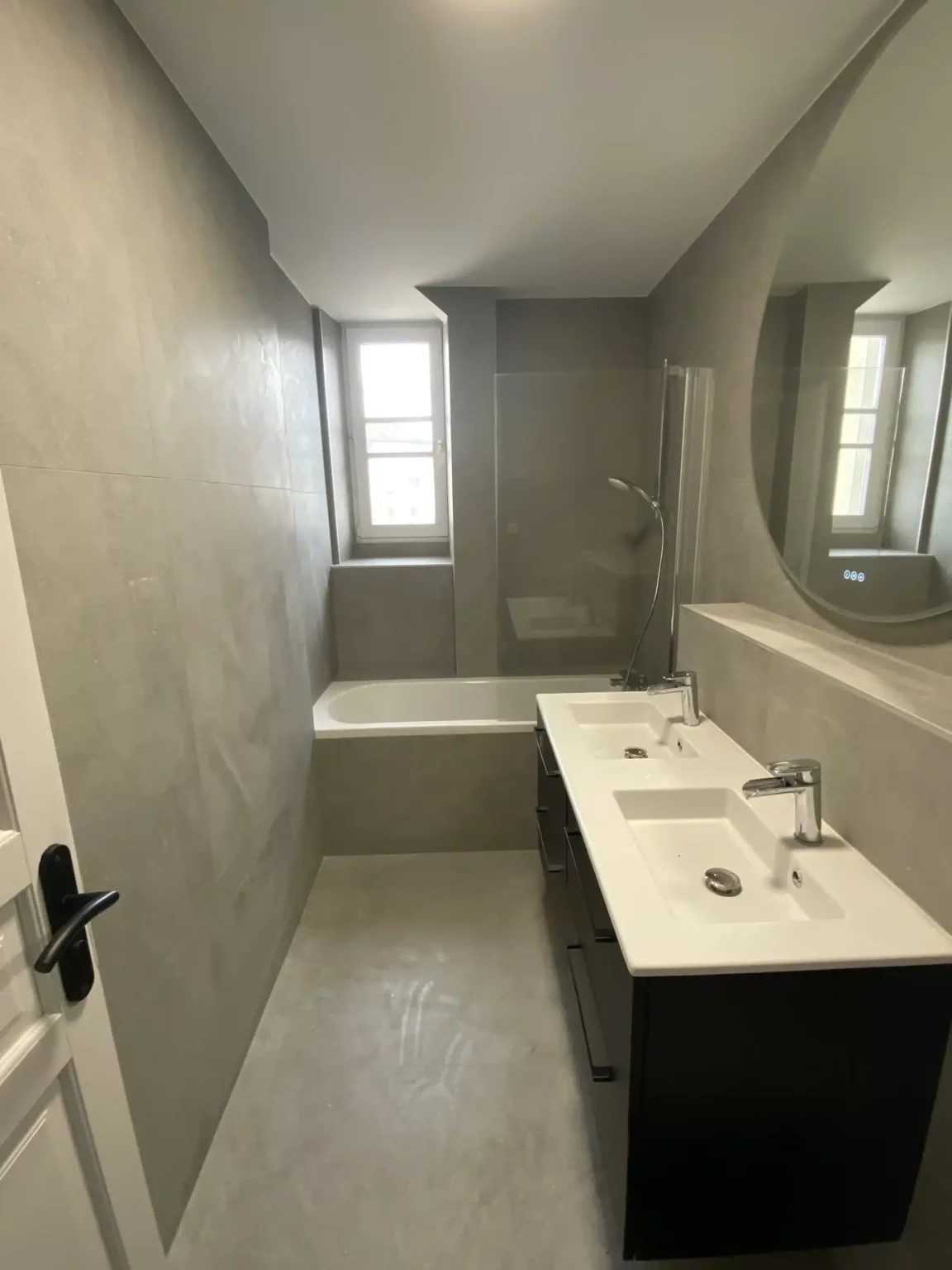 Salle de bains rénovée à Annemasse avec double vasque et baignoire intégrée.