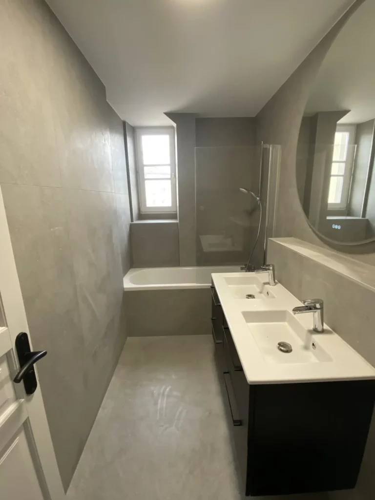 Salle de bains rénovée à Annemasse avec double vasque et baignoire intégrée.
