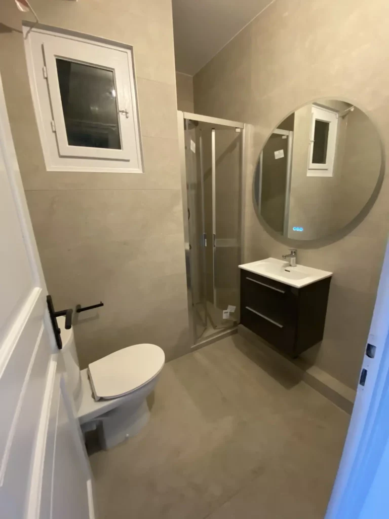 Petite salle de bains rénovée à Annemasse avec douche vitrée et carrelage beige contemporain.