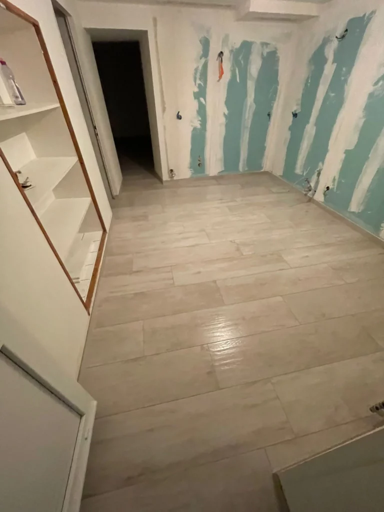 Carrelage imitation bois posé dans une pièce en cours de rénovation à Bons-en-Chablais, murs en préparation.