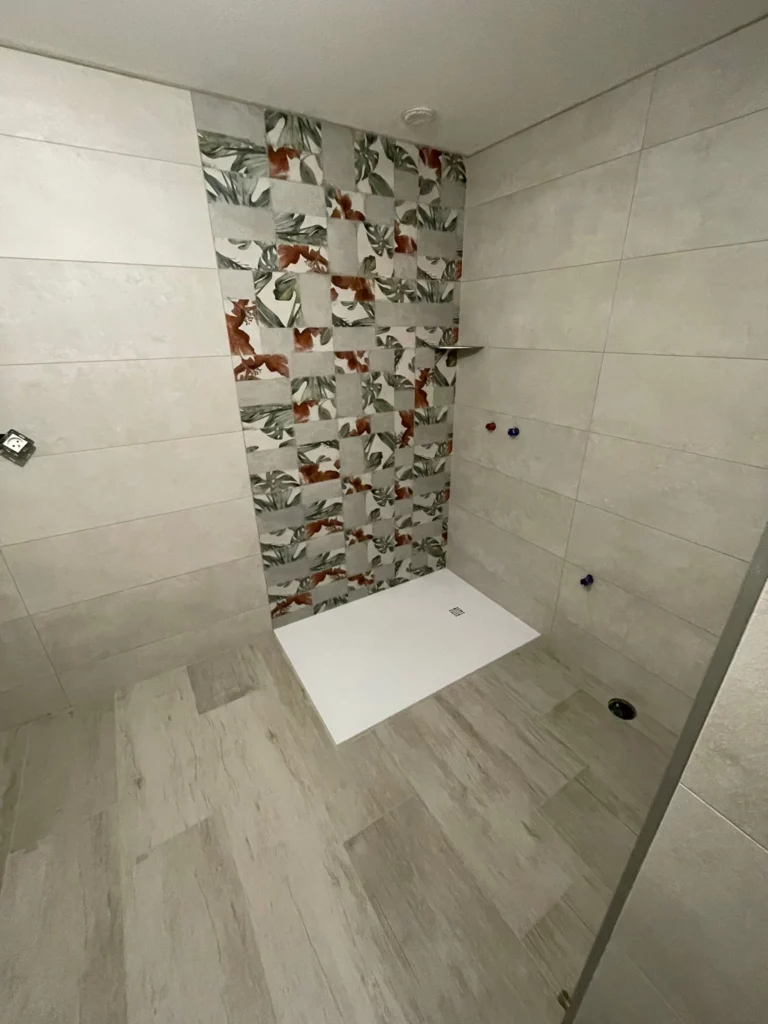 Douche avec carrelage décoratif à motifs feuillage et sol imitation bois à Bons-en-Chablais.