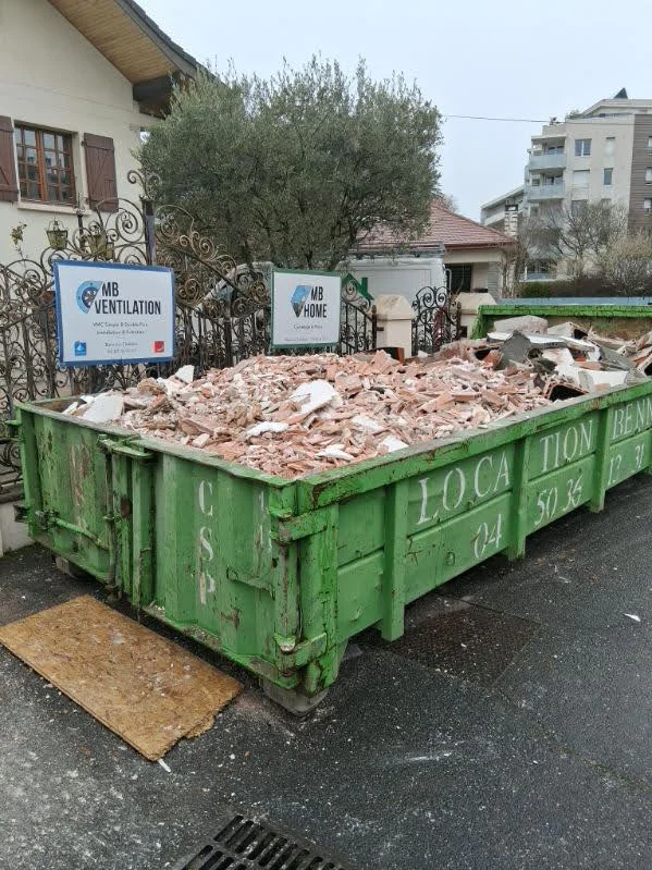 Benne verte remplie de gravats de briques et plâtre provenant d'une démolition à Annemasse.