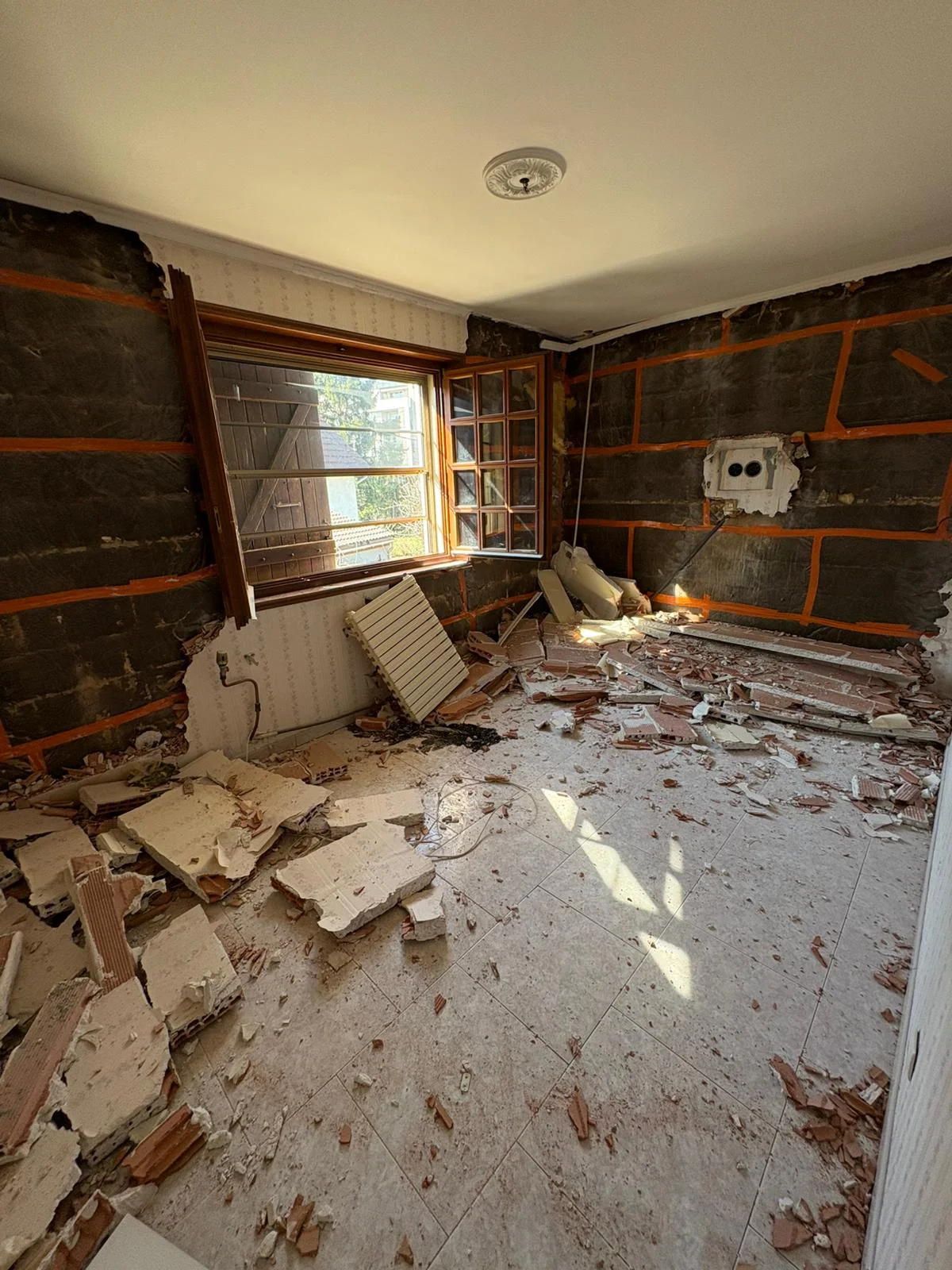 Curage intérieur et démolition d'une grande maison à Annemasse avec vue sur les murs isolés et gravats au sol.