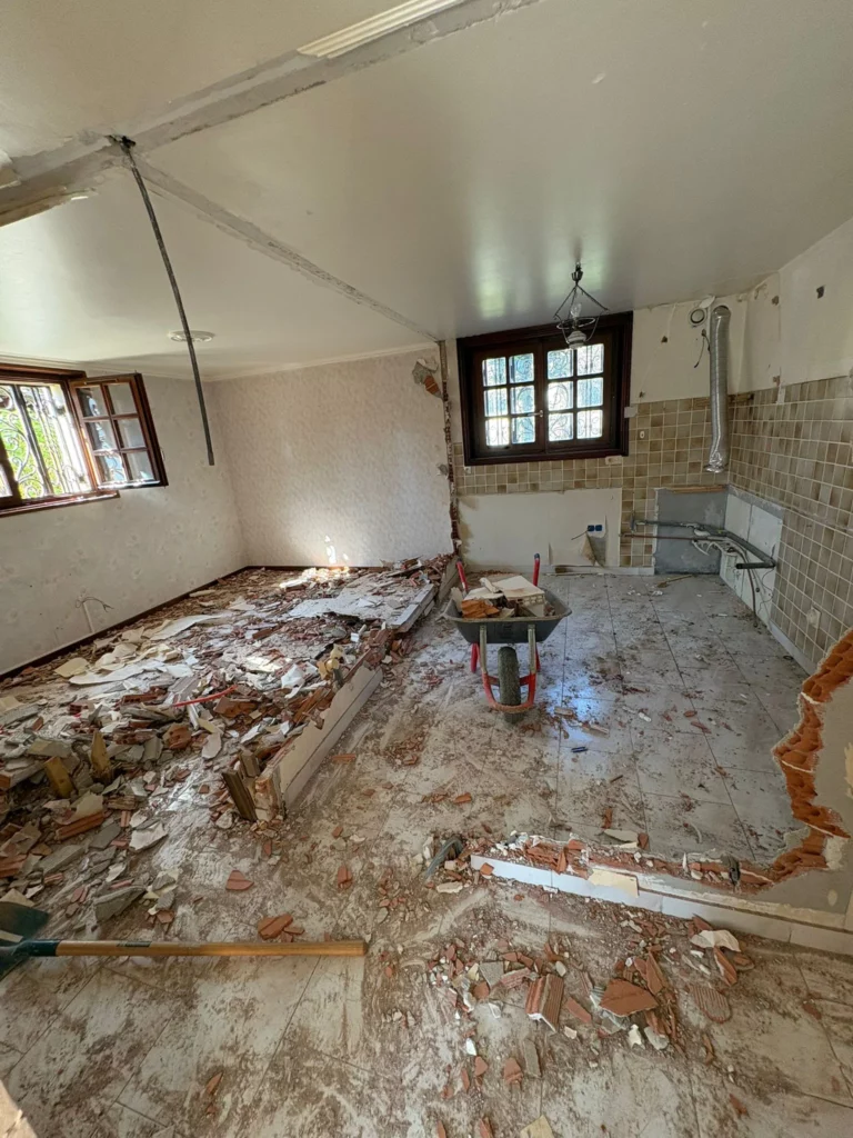 Travaux de démolition d'une grande maison à Annemasse : brouette au centre d'une pièce aux murs abattus.