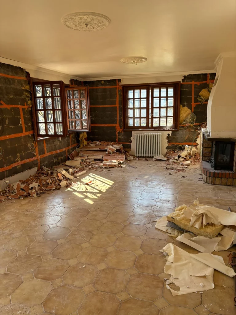 Chantier de démolition d'une grande maison à Annemasse montrant un salon dévasté et sa cheminée.