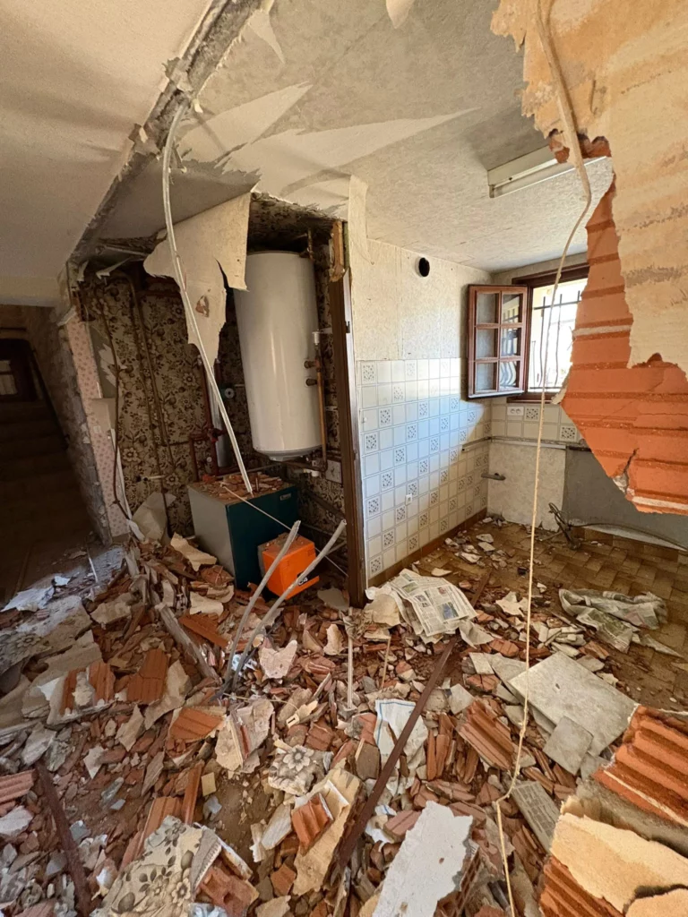 Démolition d'une grande maison à Annemasse : gros plan sur l'ouverture d'un mur en briques.