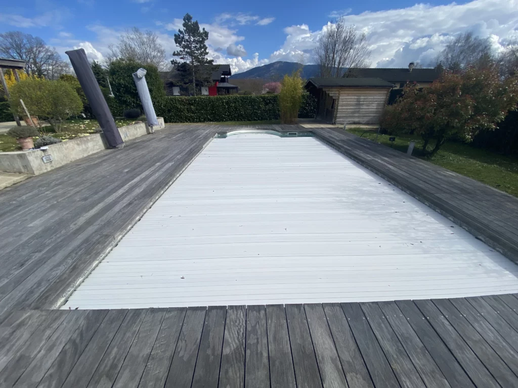 Avant la rénovation du carrelage autour d'une piscine à Veigy : ancienne terrasse en bois vieilli.