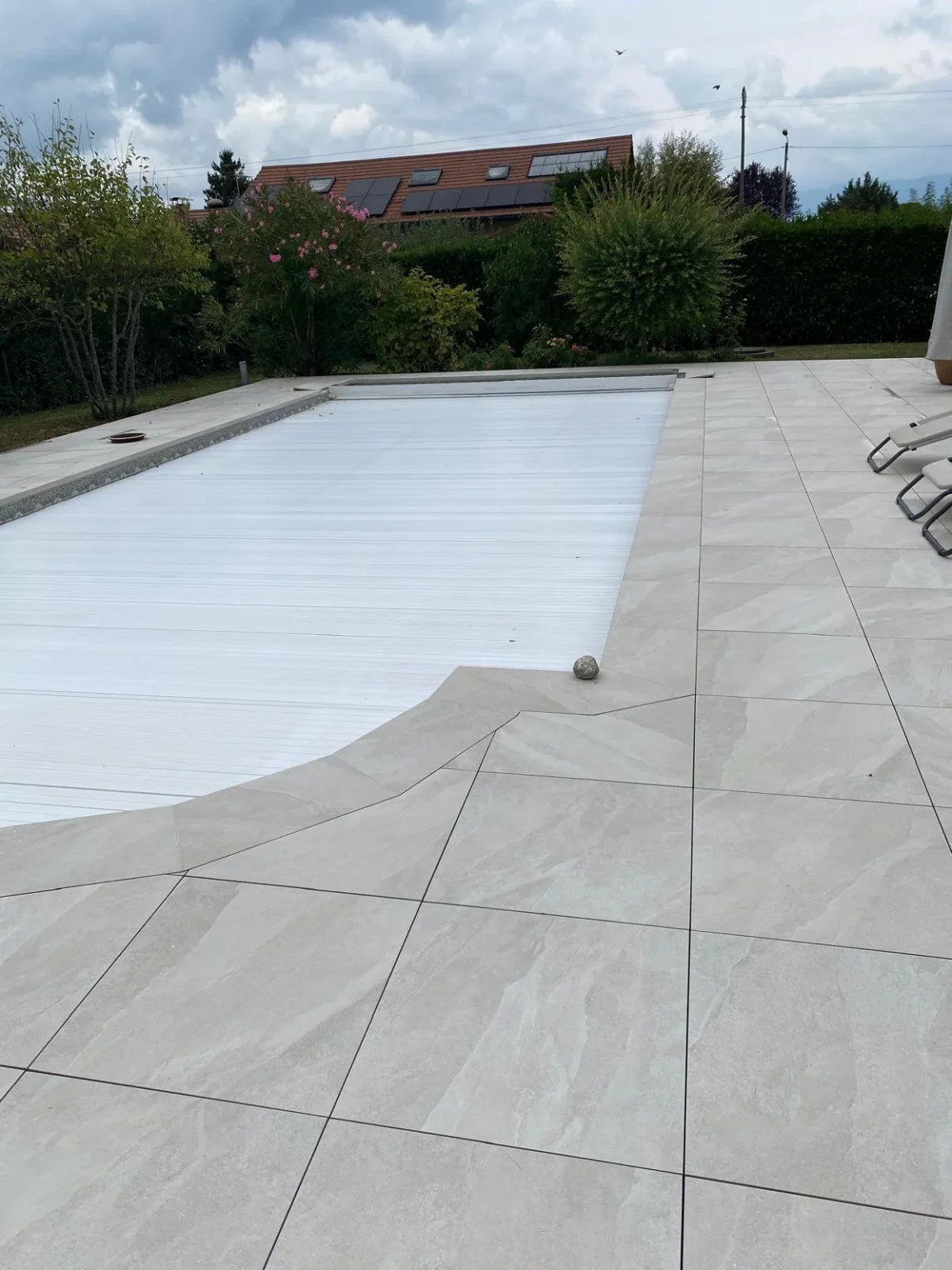 Résultat de la rénovation du carrelage autour d'une piscine à Veigy avec de grands carreaux clairs.