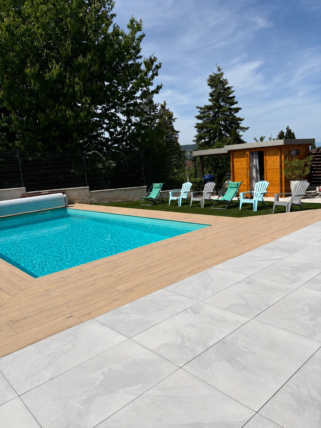 Terrasse neuve carrelée à Bons-en-Chablais avec piscine, carrelage imitation bois et salon de jardin
