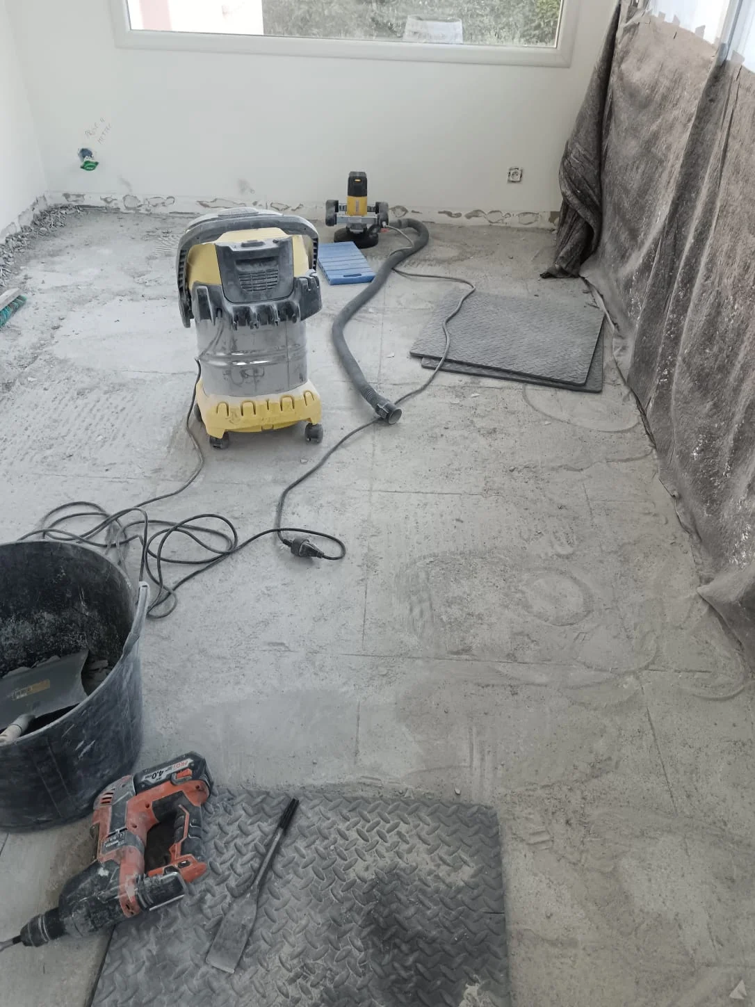 Démolition du carrelage à Excenevex : aspirateur industriel et outillage sur chape nue en cours de rénovation