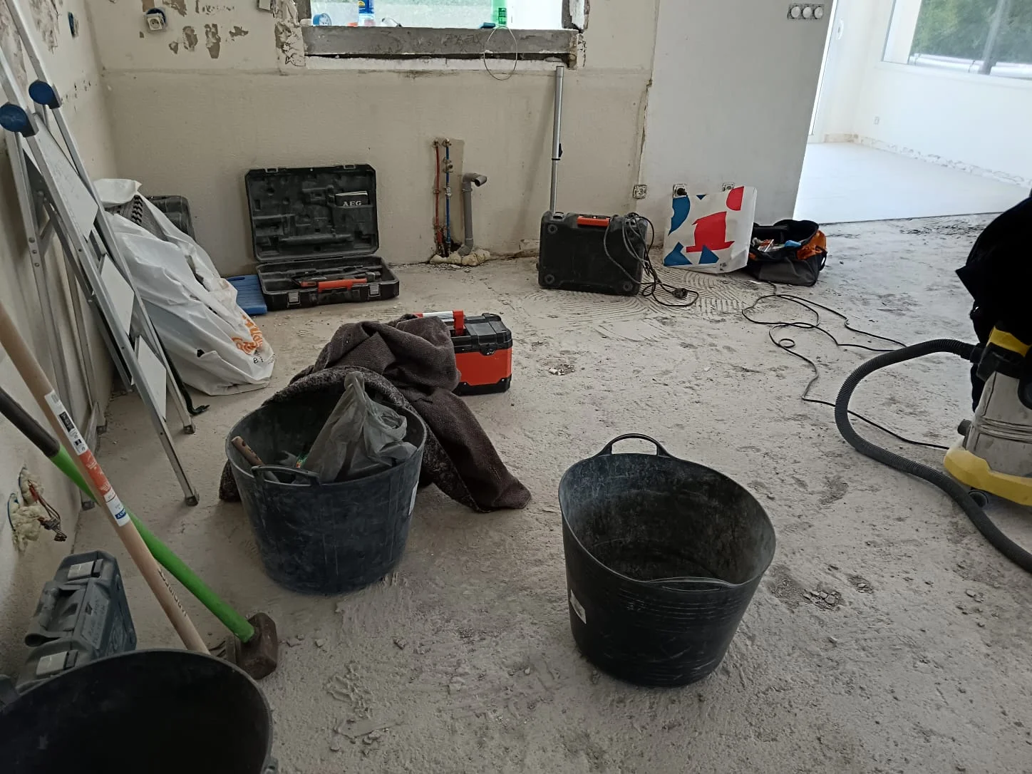 Démolition du carrelage d'une maison à Excenevex : pièce vidée avec outillage professionnel et chape dégagée