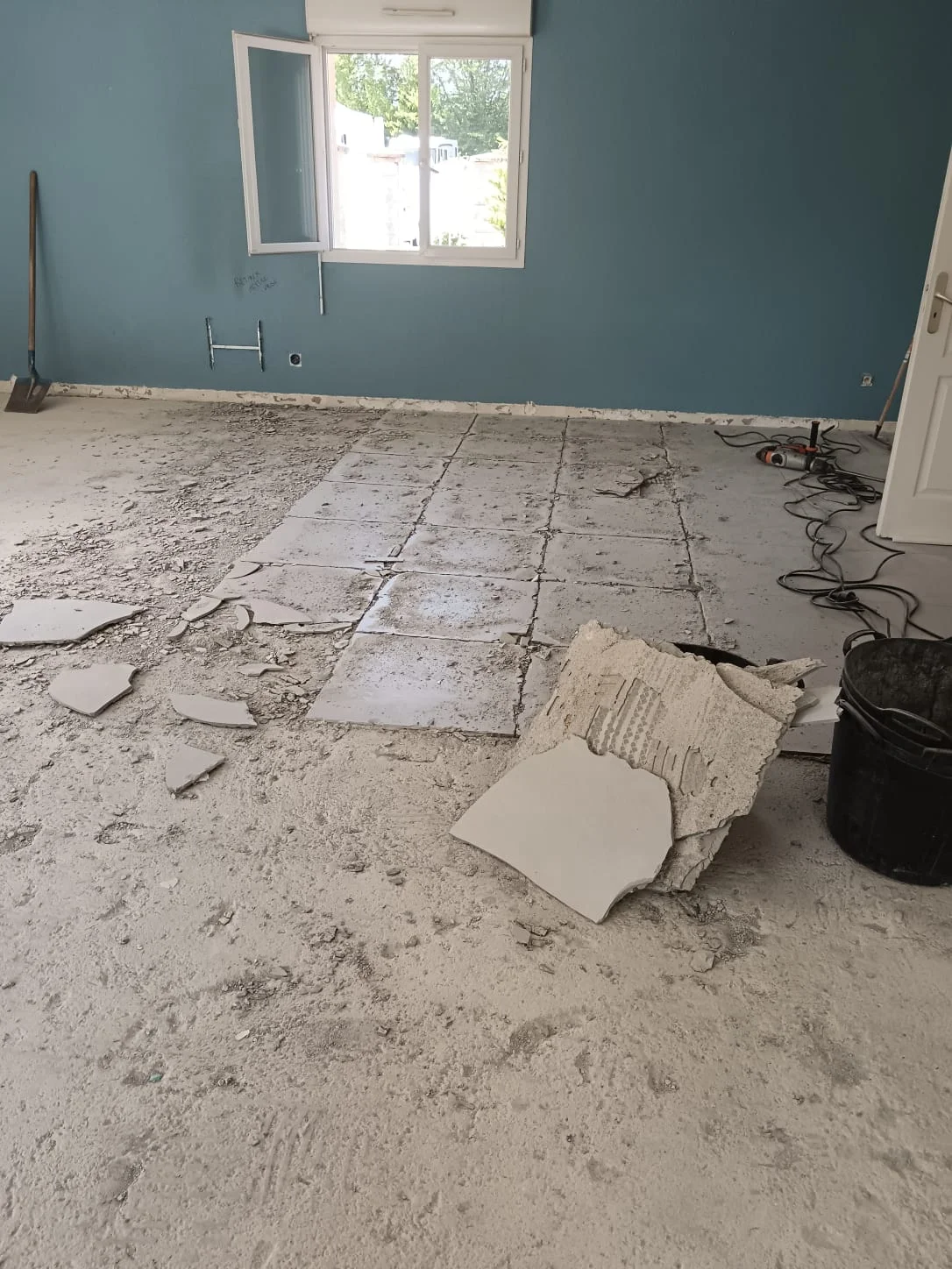 Démolition du carrelage d'une maison à Excenevex : carreaux brisés et gravats éparpillés dans un salon