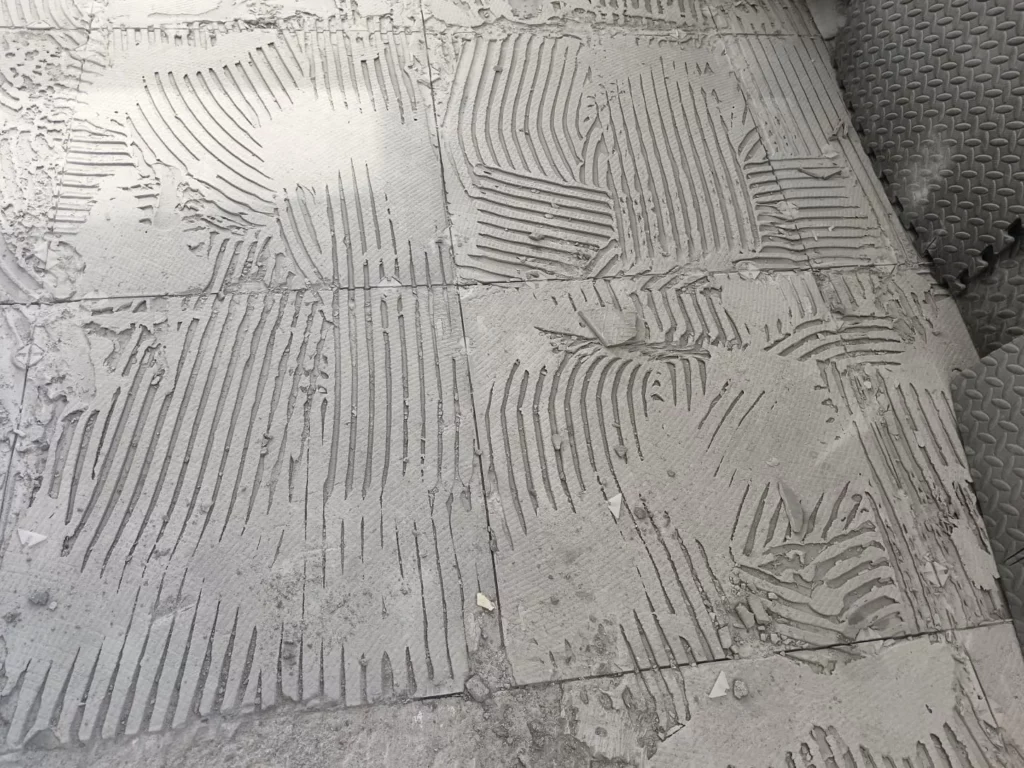 Démolition du carrelage à Excenevex : détail de la chape brute avec traces de colle à peigne après dépose