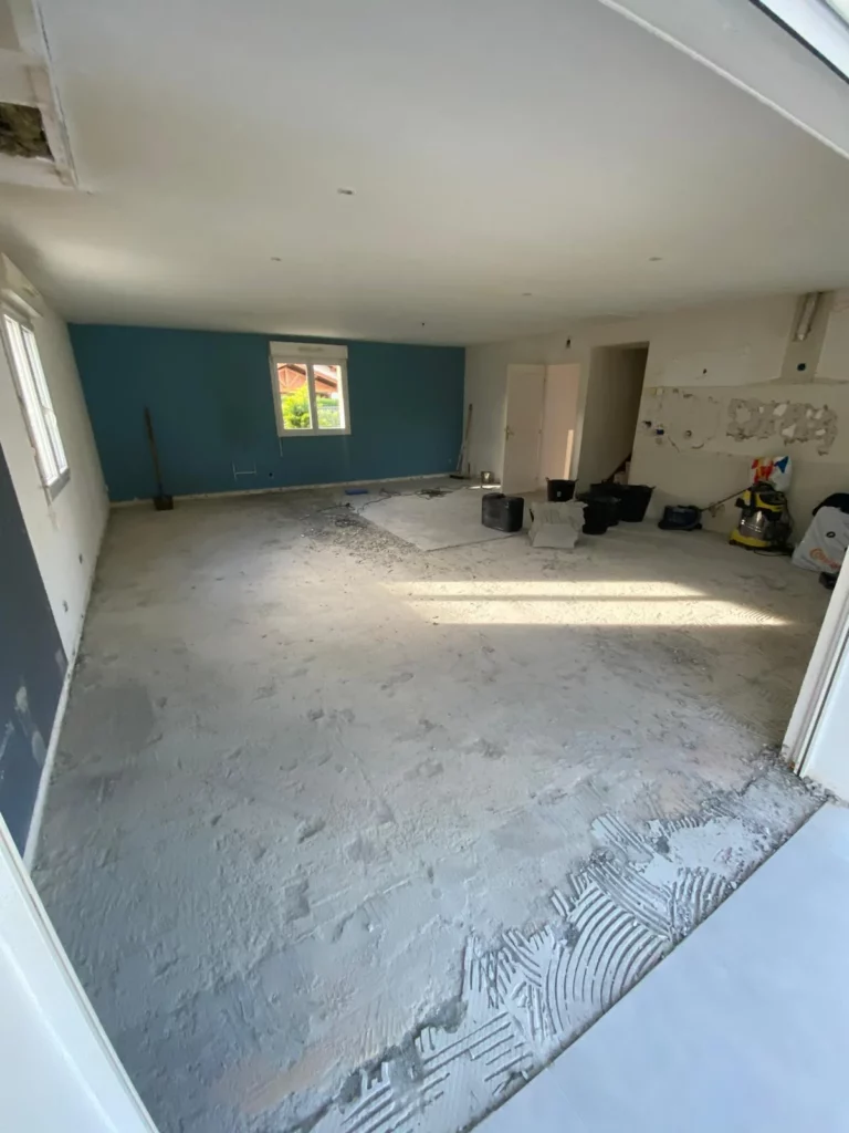 Démolition du carrelage d'une maison à Excenevex : vue d'ensemble du salon avec sol nu et matériaux de chantier