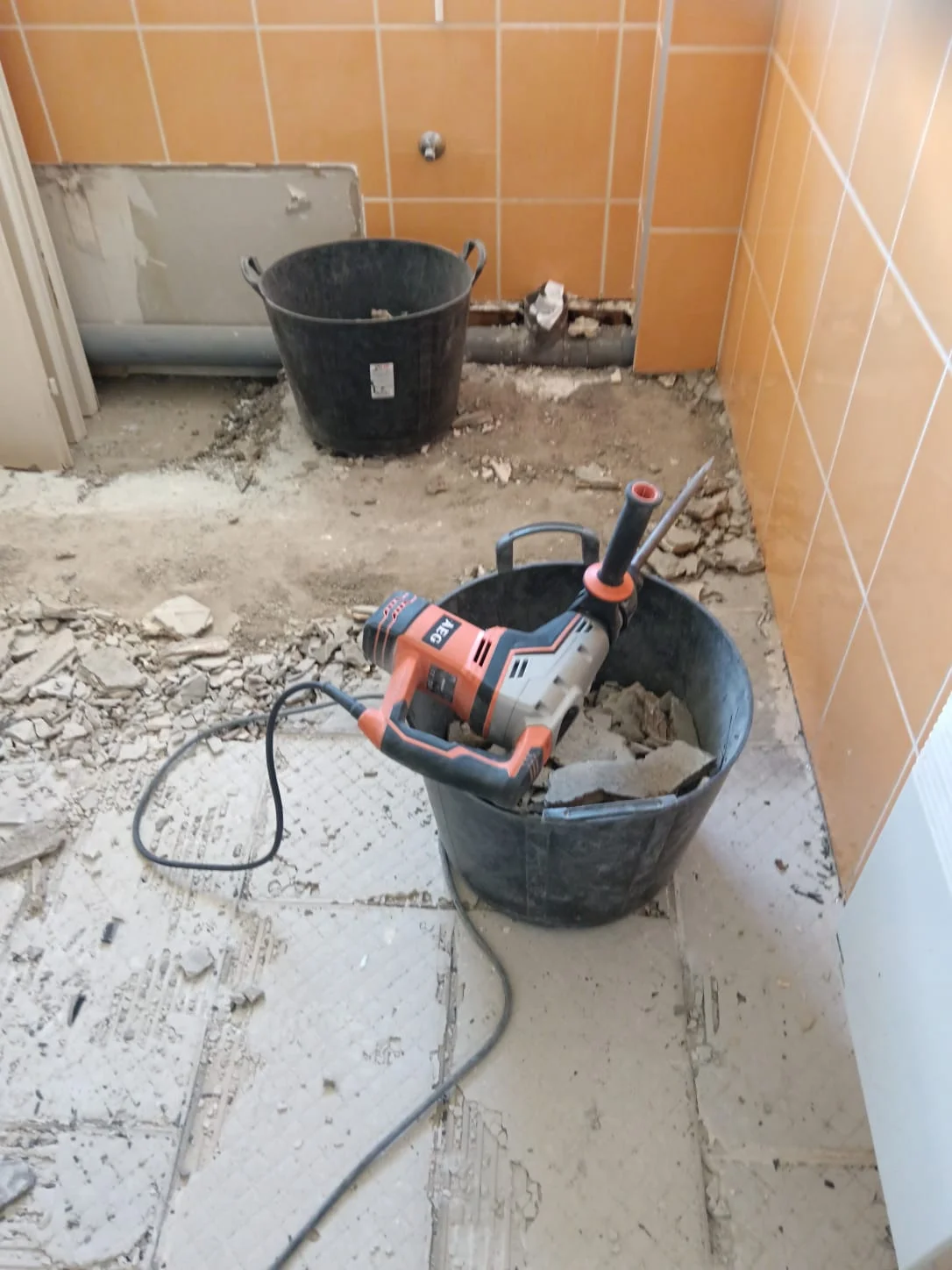 Démolition du carrelage salle de bain à Excenevex : burineur AEG dans un seau au milieu des gravats