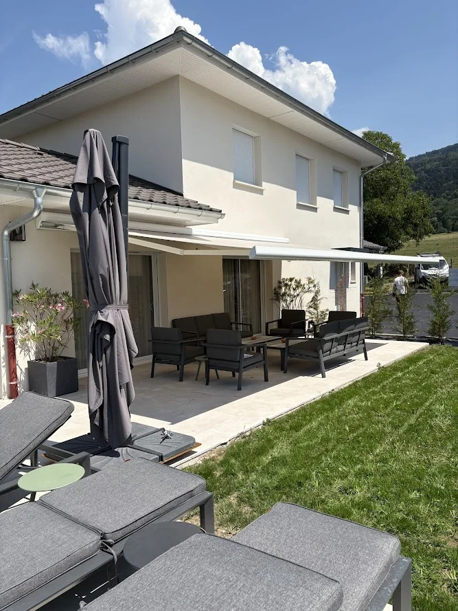 Mobilier de jardin installé sur la terrasse en carrelage à Brenthonne devant la maison