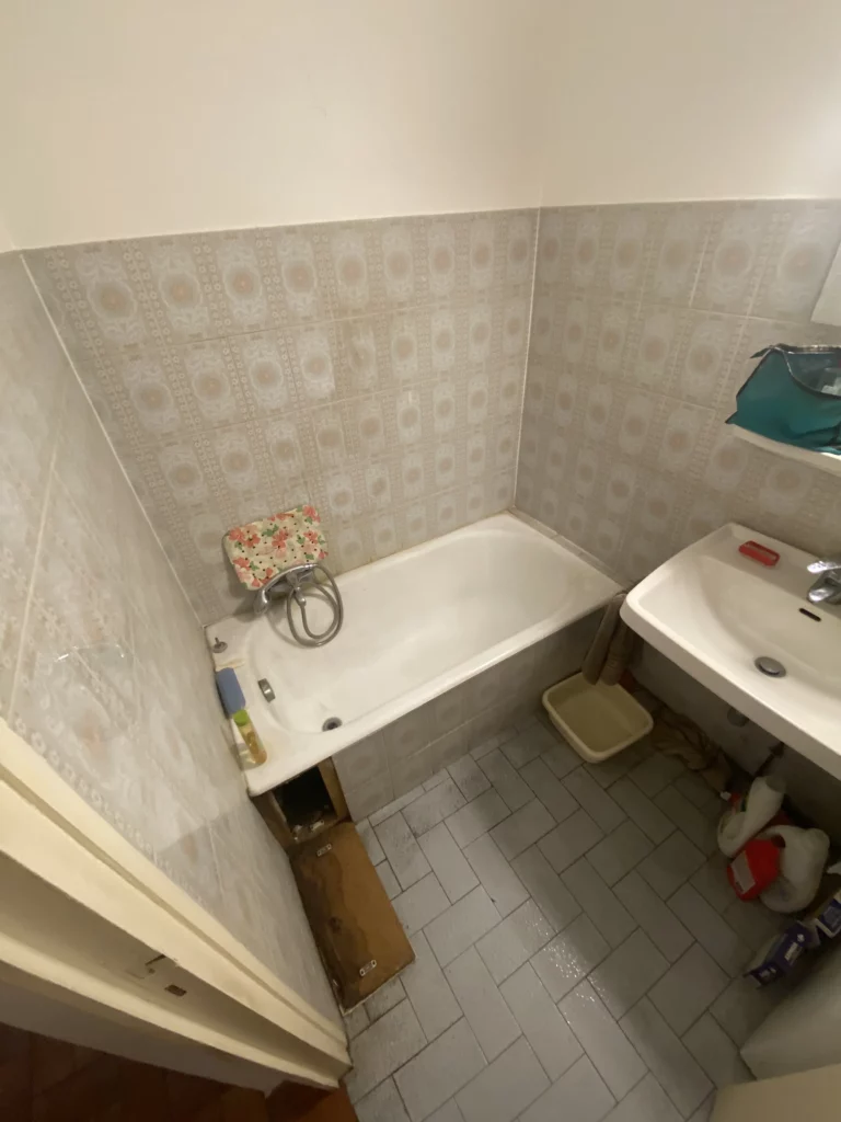 Avant rénovation d'une salle de bain à Douvaine : ancienne baignoire, faïence à motifs et lavabo vétuste