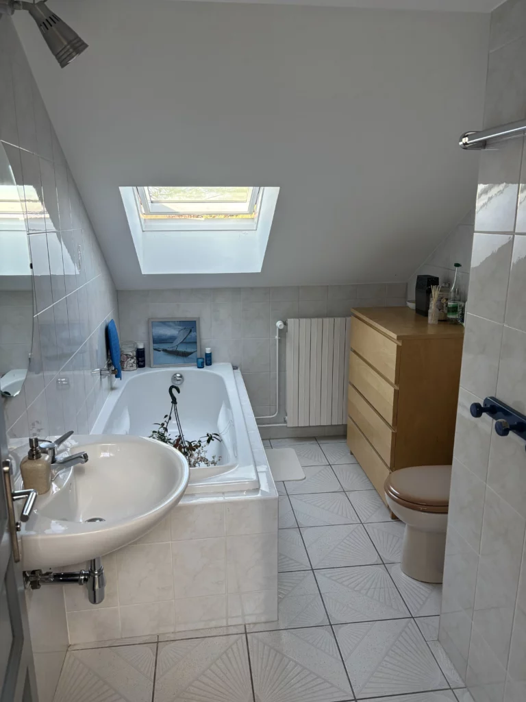 Rénovation d'une salle de bain à Fessy : baignoire, lavabo et commode en bois avant travaux sous velux